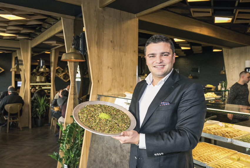 Ahmet in zijn restaurant met een schotel Baklava